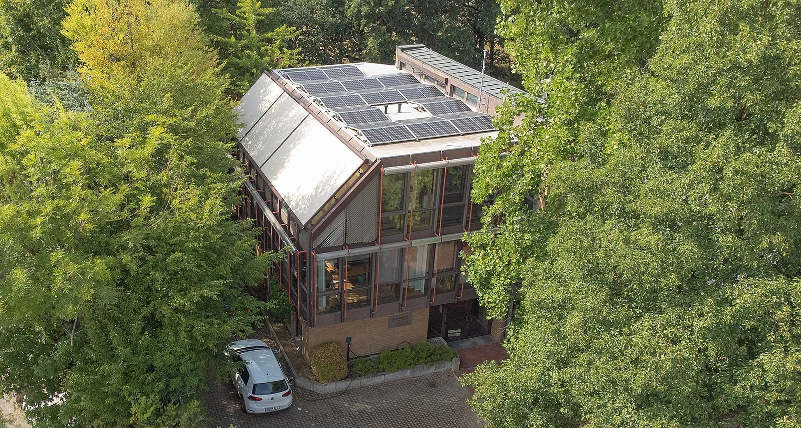 Luftbild des Firmensitzes von dialog EDV in Hannover mit Solaranlage auf dem Dach, umgeben von Bäumen