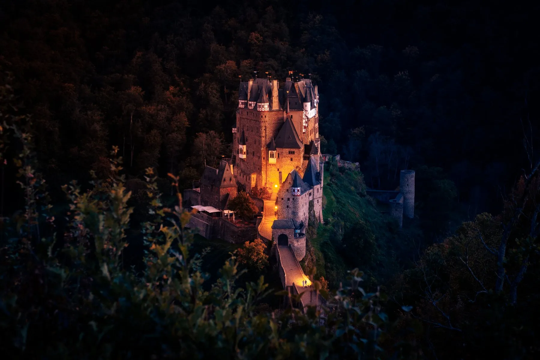 Beleuchtete Burg Eltz bei Nacht im Wald