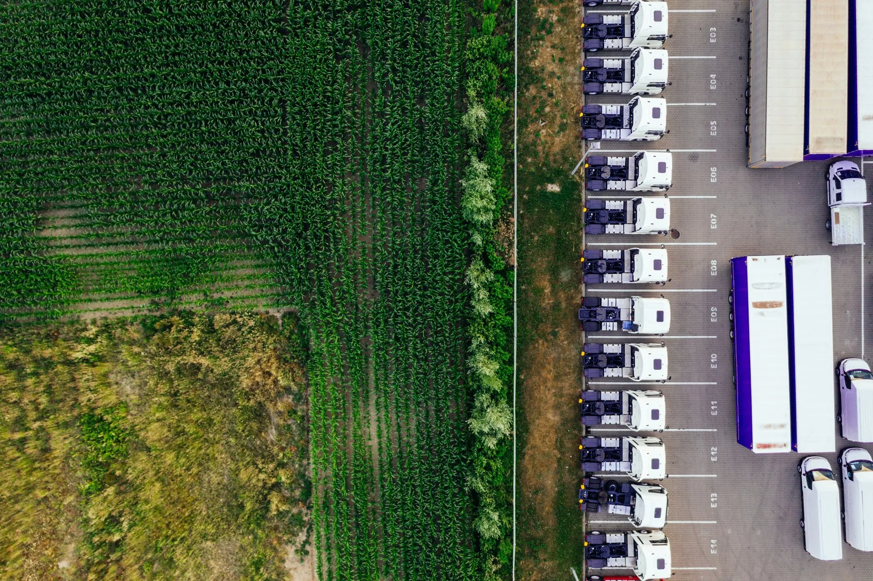 Luftbild eines Logistikhofs mit Lastwagen neben Feldern