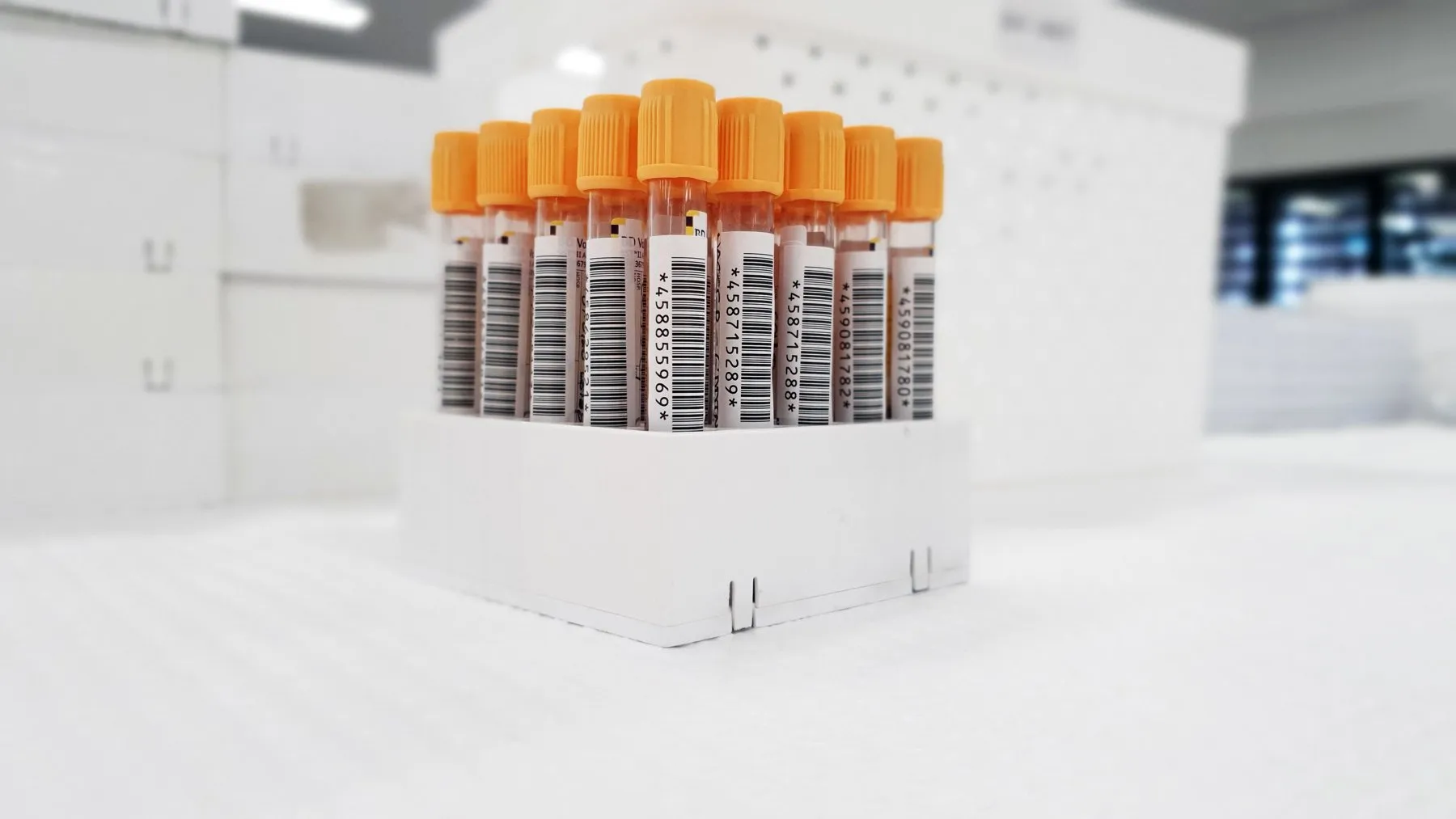 Probenröhrchen mit orangefarbenen Deckeln und Barcode-Etiketten in einem Ständer